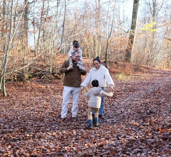 Family walking on a leaf-covered path in autumn