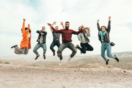 six group of people jumping on hill